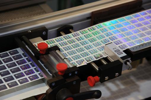 Contoh desain kemasan dengan fitur anti-pemalsuan seperti hologram dan kode QR